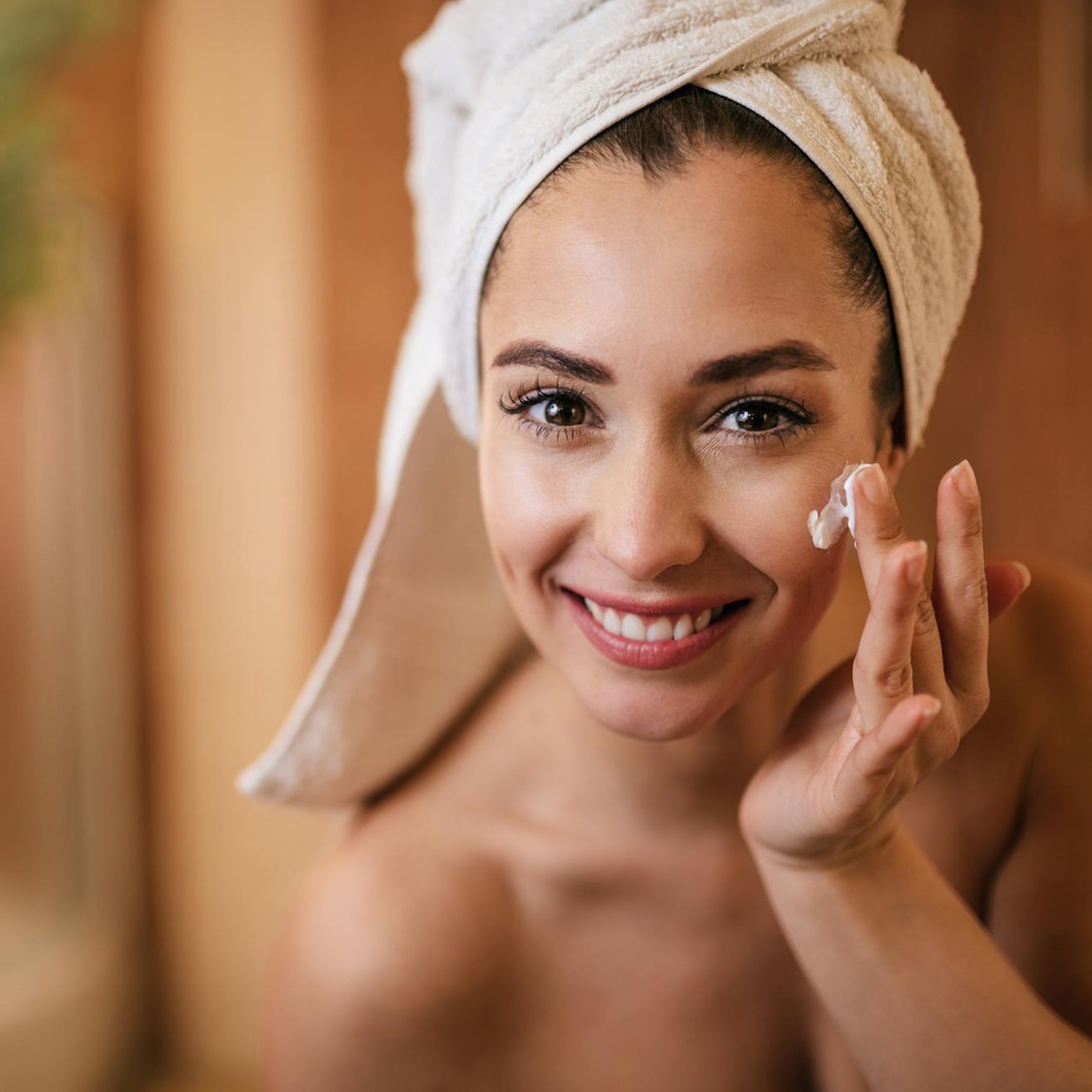 Woman applying moisturiser to maintain even tan