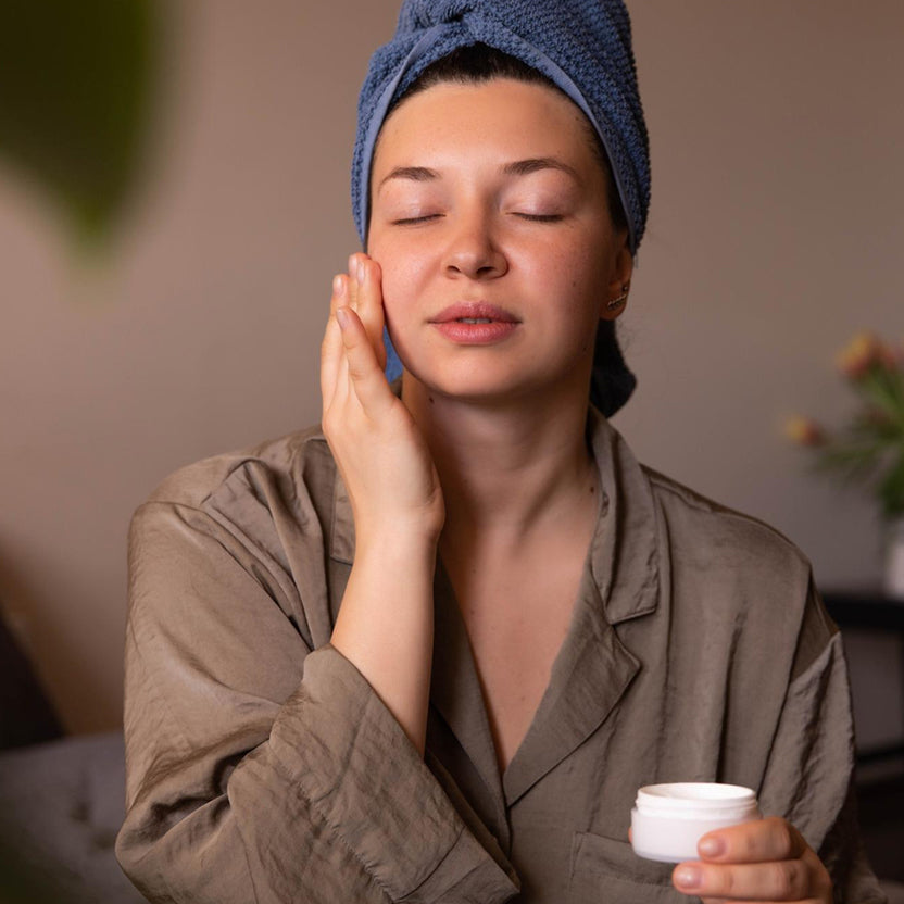 Woman applying moisturiser to support healthy glow
