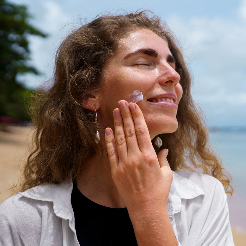 Woman applying moisturiser to maintain even tan
